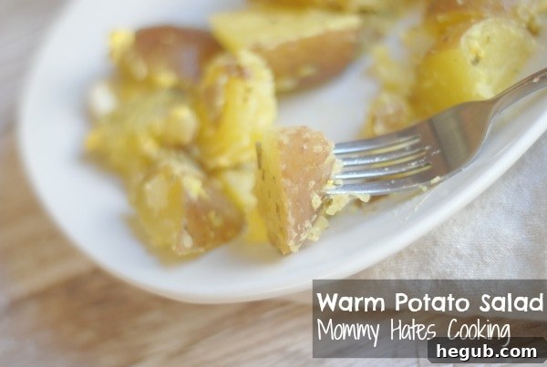 A bowl of delicious warm potato salad, garnished with fresh herbs