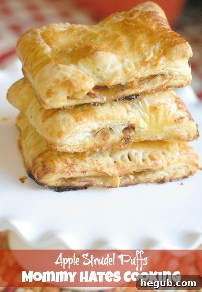 Close-up of a single apple strudel puff with its flaky crust and apple filling visible, resting on a serving plate.