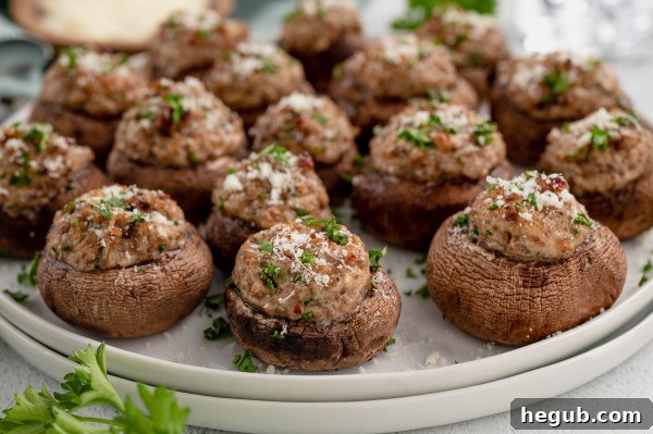 A close-up of several perfectly baked and golden-brown Stuffed Portobello Mushrooms, garnished with vibrant fresh green parsley, artfully arranged on a serving dish.