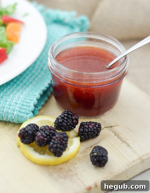 Blackberries being pressed through a mesh strainer for vinaigrette