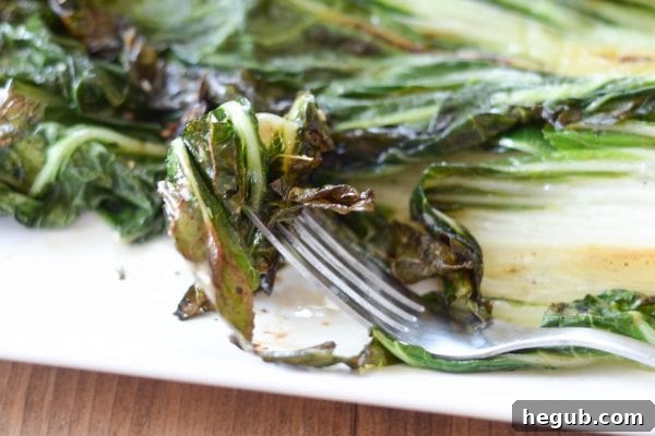 Close-up of grilled bok choy, showing its wilted green leaves and slightly browned stems.