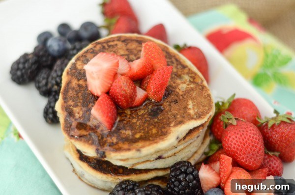 A stack of Gluten-Free Pancakes with berries and whipped cream