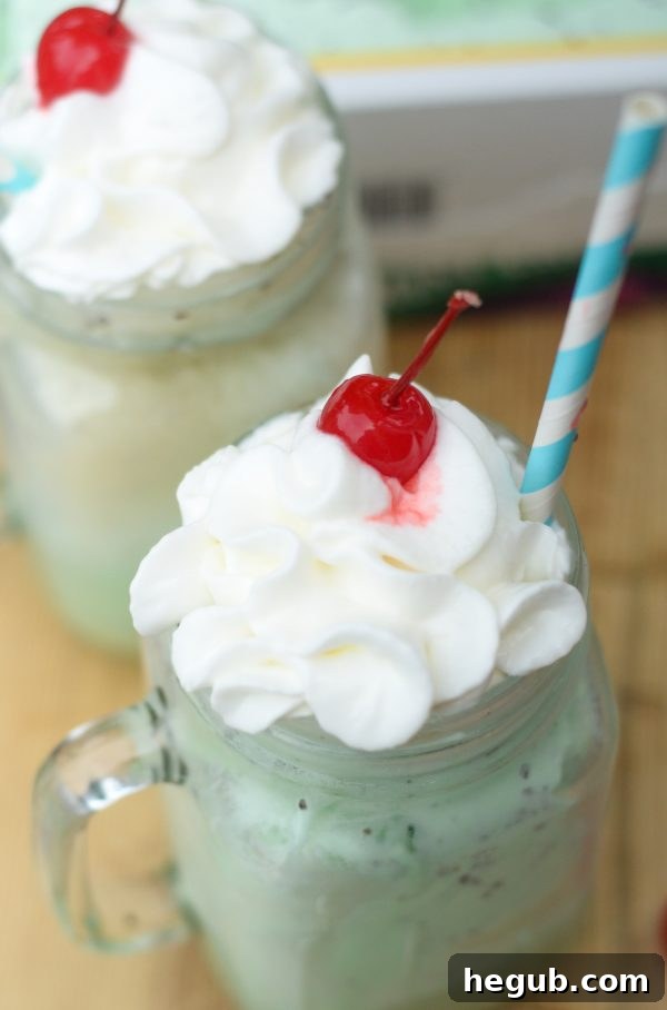 An appetizing view of multiple Mint Chocolate Floats, garnished with whipped cream and cherries, arranged to emphasize their appeal as a refreshing dessert.