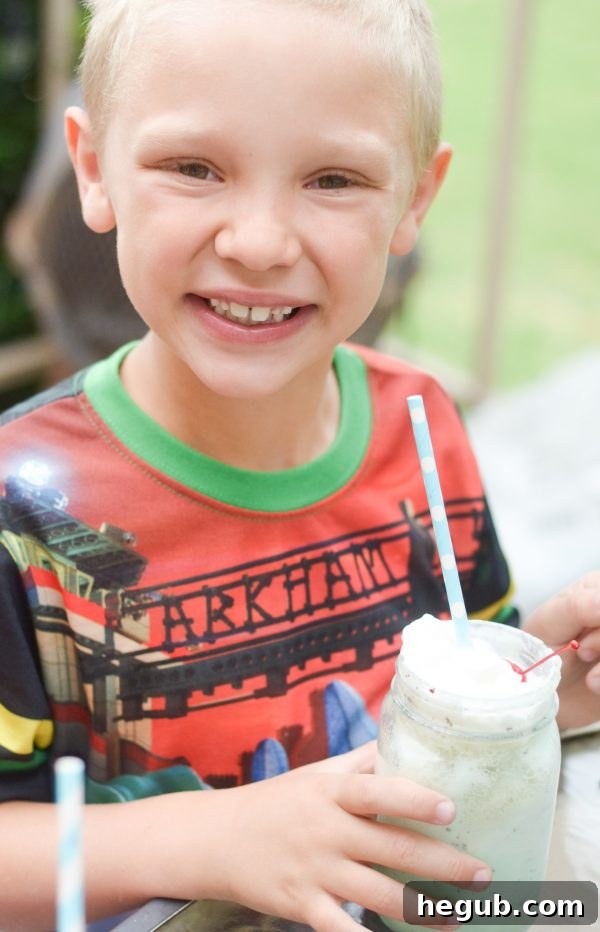 An inviting close-up of a Mint Chocolate Float, with a spoon ready to scoop into the layers of ice cream and foam, promising a cool and delicious escape.