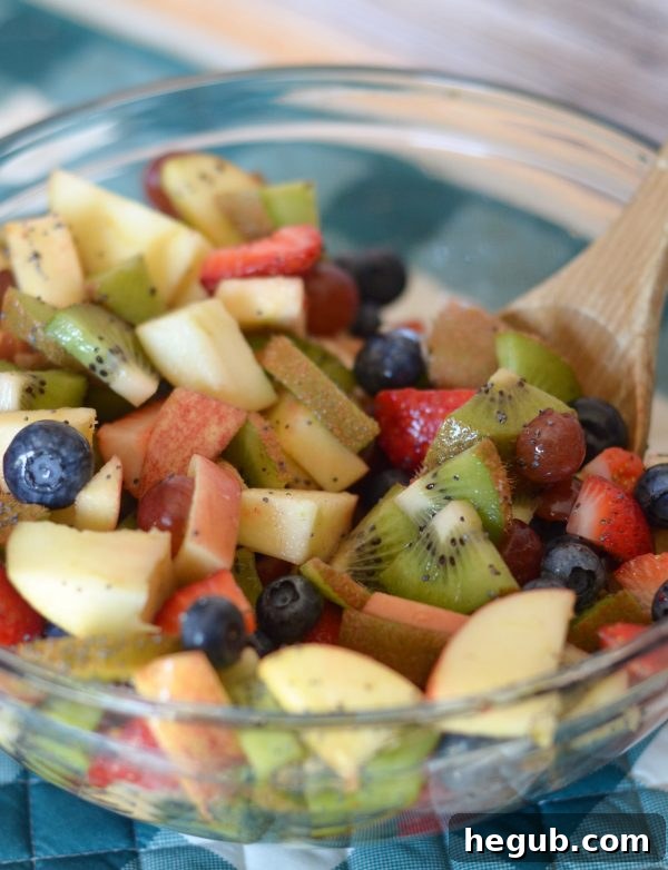 Effortless Poppy Seed Fruit Medley 2 A vibrant bowl of Poppy Seed Fruit Salad, featuring sliced kiwi, strawberries, grapes, blueberries, and apples, garnished with poppy seeds and a lime slice. It looks incredibly fresh and inviting, perfect for a summer gathering.
