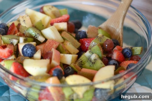 Effortless Poppy Seed Fruit Medley 4 Overhead view of a prepared Poppy Seed Fruit Salad in a white bowl, ready to be served. The bright colors of the fruit and the delicate poppy seeds are clearly visible.