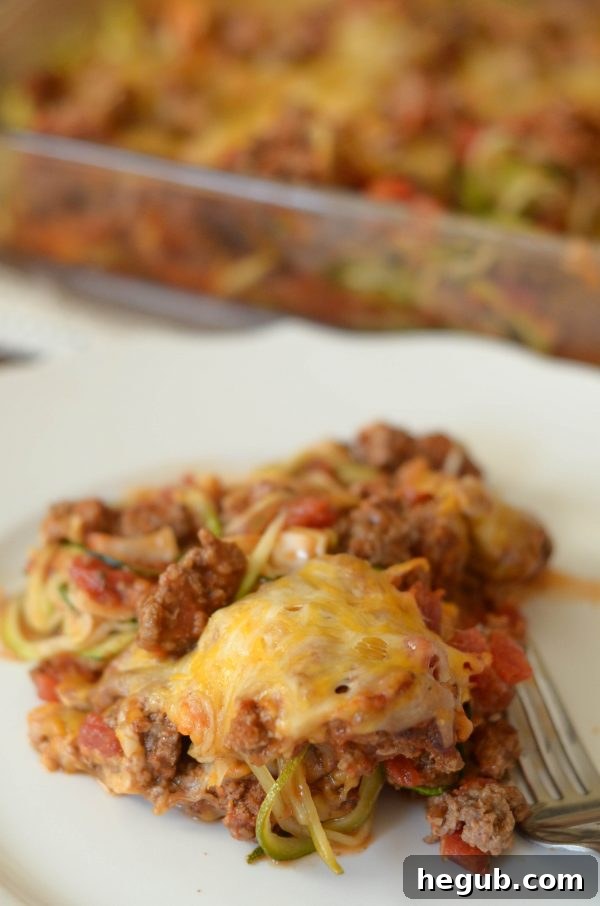 Layered Taco Zoodle Casserole with ground beef, sauce, and cheese.