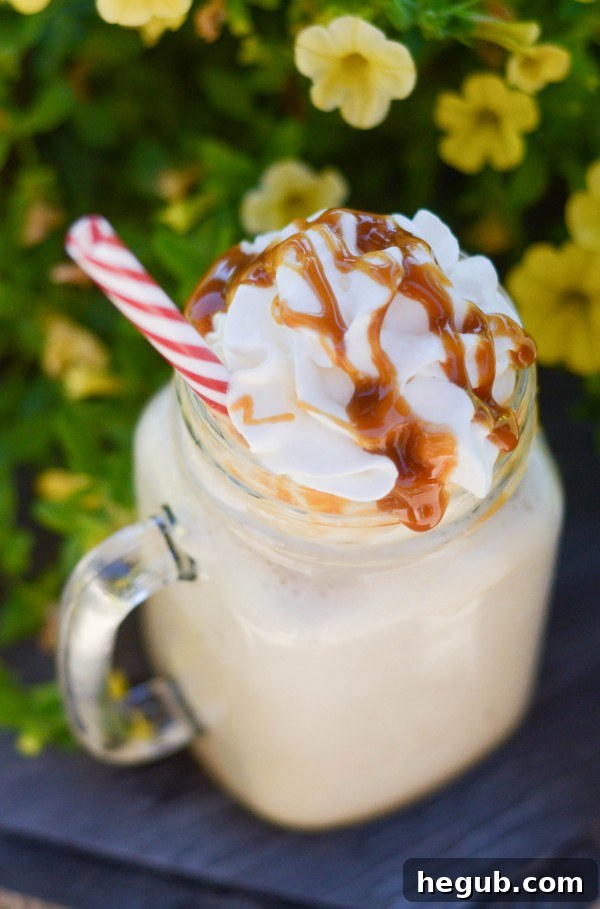 A tall glass of homemade Frozen Caramel Coffee topped with whipped cream and a generous drizzle of caramel sauce, perfect for a refreshing treat.