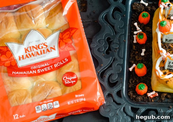 A child's hands decorating a Spooky Graveyard Roll with icing and candy