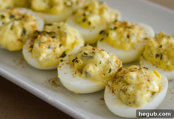 A close-up of a single deviled egg, showcasing the perfectly piped filling and a generous sprinkle of paprika, ready to eat.
