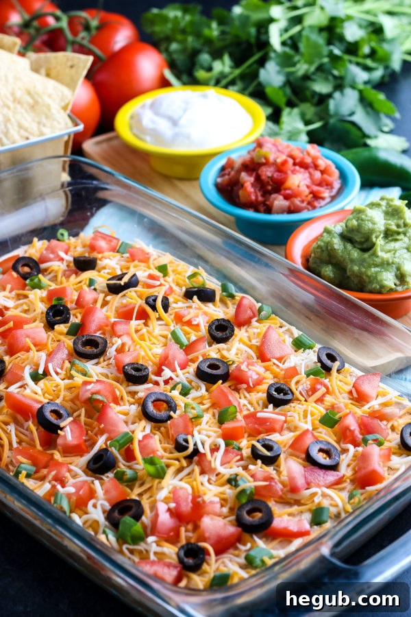 Layered Taco Dip with fresh toppings in a glass dish