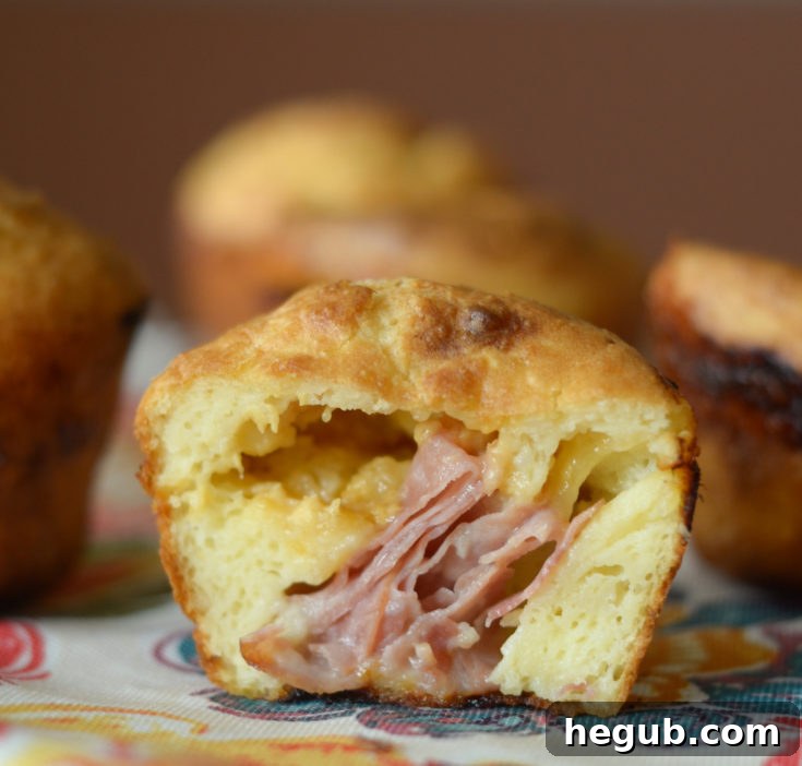 Golden brown ham and cheese stuffed popovers on a baking sheet.