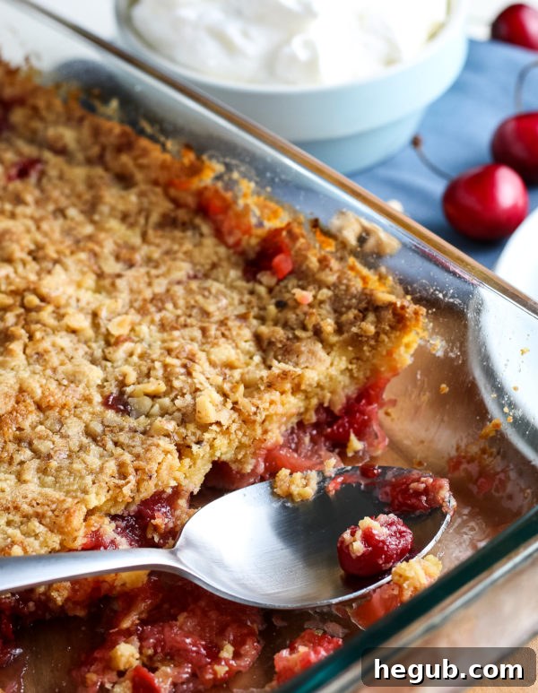 A baking dish with layers of cherry pie filling and cake mix, ready for butter