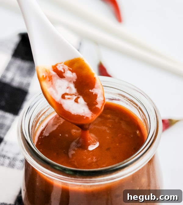 Delicious and easy homemade hoisin sauce in a bowl with a spoon, garnished with sesame seeds.