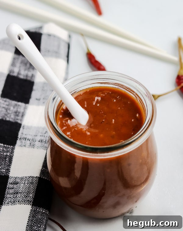 A small saucepan on a stove with hoisin sauce ingredients being whisked together.