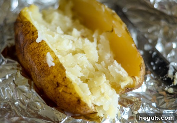 Several smoked baked potatoes ready to be unwrapped and topped