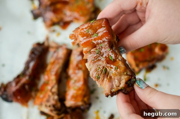 This image shows someone about to eat a slow cooker baby back ribs with apple barbecue sauce.