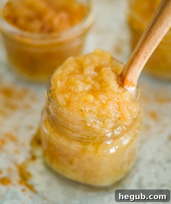 Three glass jars filled with homemade pressure cooker applesauce, topped with lids.